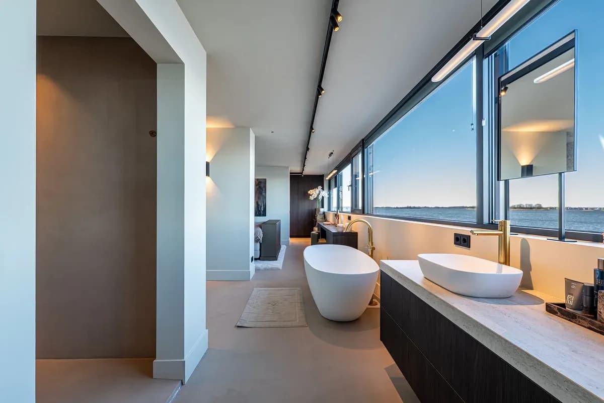 Badkamer met vrijstaand bad, wastafelmeubel en uitzicht over het water